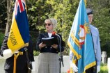 A blond haired woman gives a speech between two flags, one for the city of Harrogate and the other featuring the union jack.