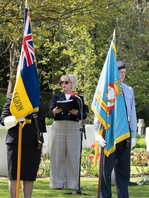 A blond haired woman gives a speech between two flags, one for the city of Harrogate and the other featuring the union jack.