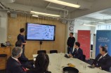 Members of the Japanese delegation sitting around a table, looking at a presentation on a screen.