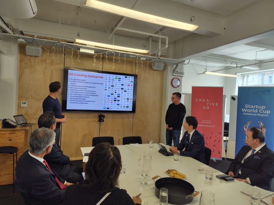 Members of the Japanese delegation sitting around a table, looking at a presentation on a screen.