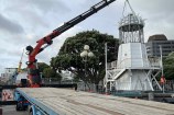The iconic lighthouse slide at Frank Kitts park being removed via a truck and crane.