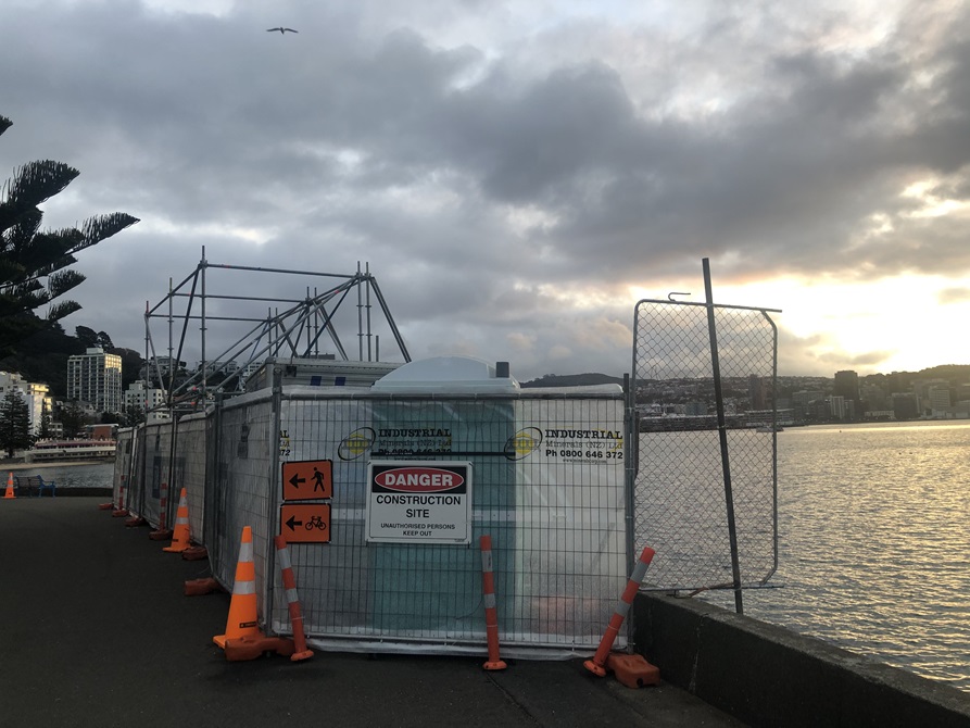Fencing and cones surrounding a portaloo and scaffolding on Oriental Bay.