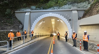 The opening of the Seatoun Tunnel with construction workers standing on either side of it. 