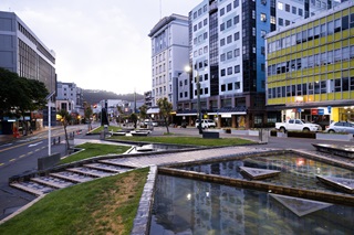 Te Aro park at the bottom of the image, showing water ponds and a walkway, buildings are behind.