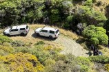 Two Council utes parked on a gravel road in the bush.
