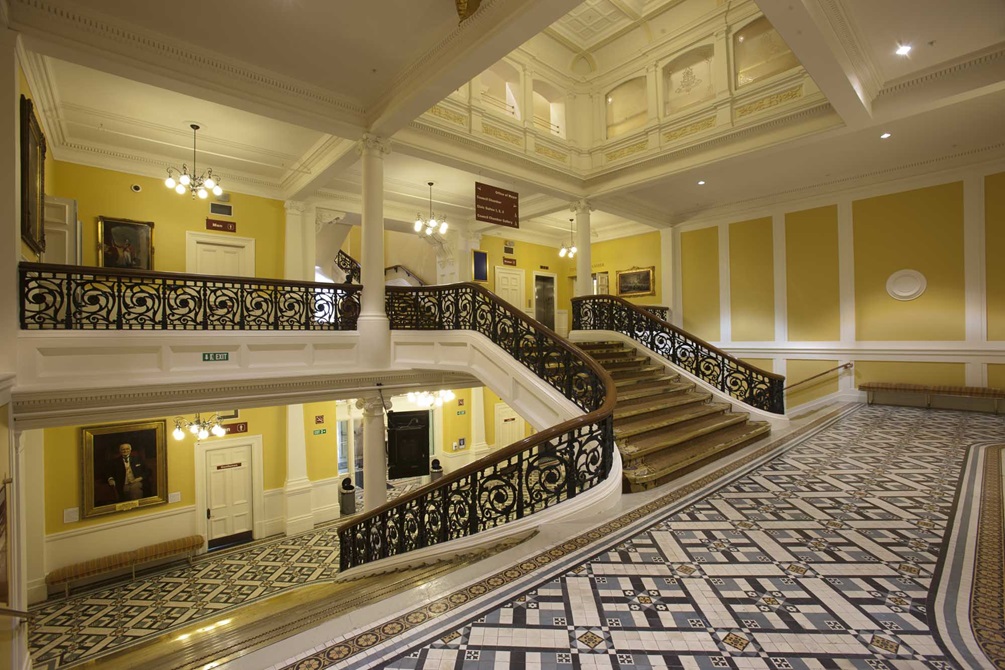 Town Hall staircase with cast-iron balustrade and encaustic geometric floor tiles.