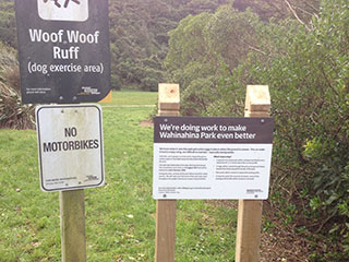 Dog exercise sign and project sign at entrance to park.