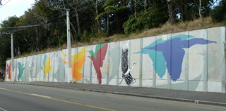 A mural on a road side wall depicting colourful birds in flight.