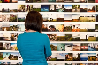Woman looking at photographs on wall. 