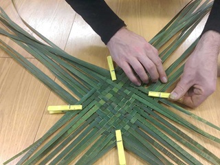 Hands weaving flax.