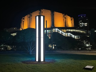 Sentinel by Tyler Jackson. A four-sided monolith glows white in the darkness with the Michael Fowler Centre lit in orange in the background.