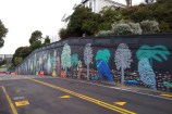 A mural on the side of the road that has colourful native birds and trees.