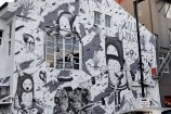 The side of a building with a black and white mural of fantasy characters.