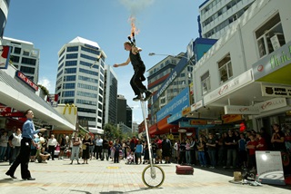 Street performer on unicycle with flaming torch.