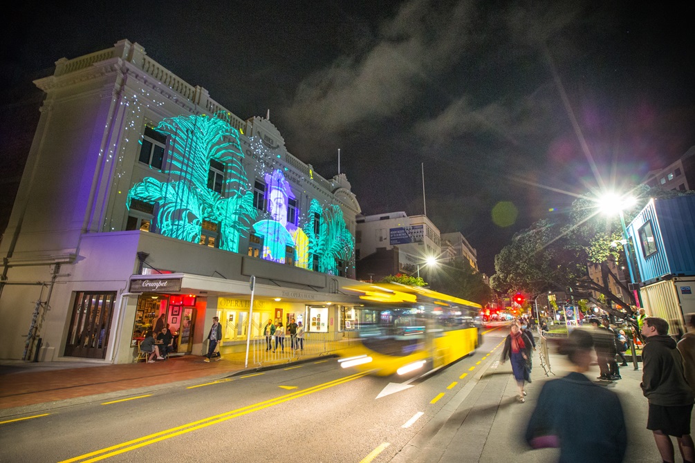 A bus travelling down Manners Street, outside the Opera House and opposite Te Aro Park as part of 'Story Box.'