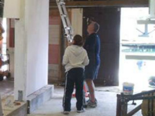 Two people lean a ladder against a wall inside the Star Boating Club.