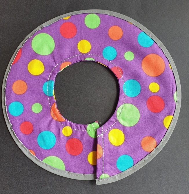A purple collar with colourful dots all over it.