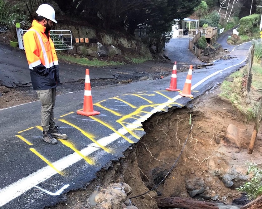 A damaged section of a road is cordoned off during a weather event.