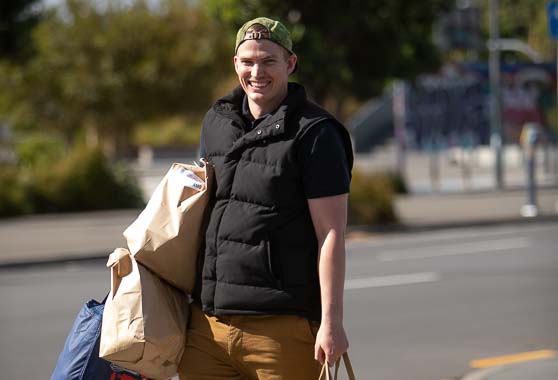 Young man carrying lots of grocery shopping bags.