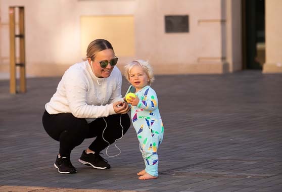 A woman and a toddler playing with a small ball in Civic Square.