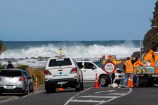 Road crews working on Wellington South Coast, with a big wave in the background.