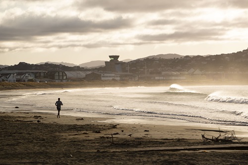 A man runs on a beach alone.