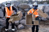 Downer construction workers holding two penguin nesting boxes