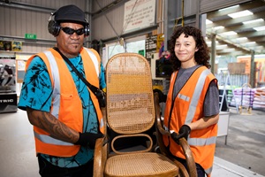 Two Tip Shop staff members holding a chair.