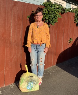 Wellington City councillor Laurie Foon standing next to a half-filled Council rubbish bag, which was the entire waste output of her family-of-four for a month.