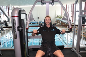 Club Active Fitness Consultant Josh Bohmer standing next to the exercise bikes that overlook Freyberg Pool.