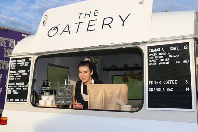 Anna Campbell looking out the front of her white caravan shop, The Oatery, where she sells porridge and granola bowls at Harbourside Market.