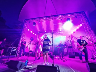 A singer and her band on stage performing in bright purple light. 