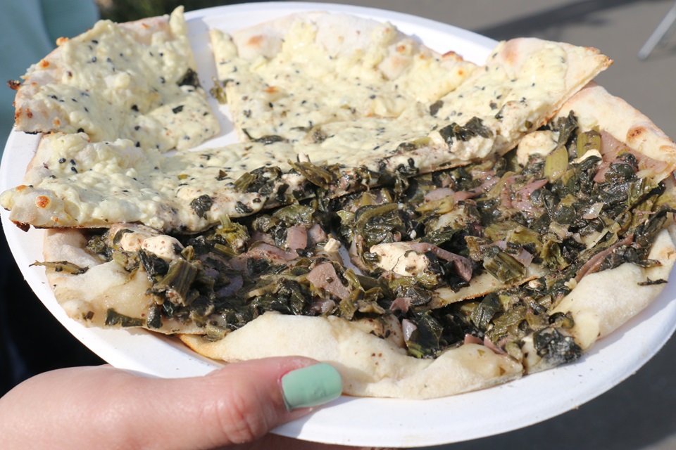 A Syrian-style pizza, manakesh, topped with spinach and feta, on a paper plate.