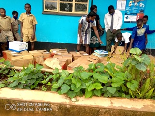 School children and teachers from Gatsi Primary School in Honde Valley, Zimbabwe, stand in front of the bright blue school room and go through boxes of books which were donated from Wellington.