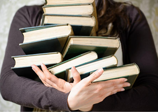 Person holding a stack of books.
