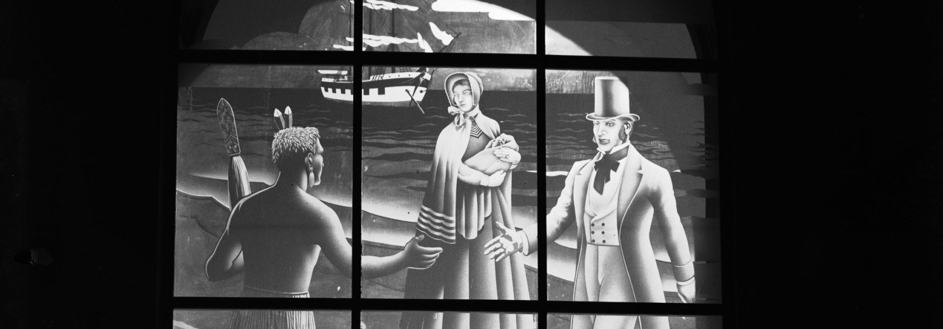 Black and white image of stain glass window showing Māori man on beach greeting pakeha man with woman holding baby with a ship in the foreground.