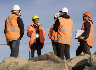 Engineer Veronica Byrne briefing four workers on a rocky site. All are wearing hi-vis and hard hats.