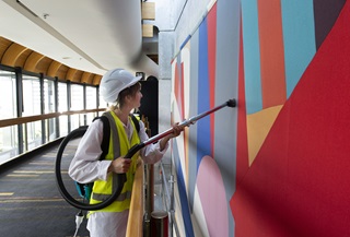 A large textile artwork by Gordon Crook being cleaned. 
