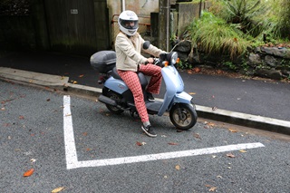 Victoria University student Daisy Lutyens on her scooter parked in a white triangle car park for small vehicles.