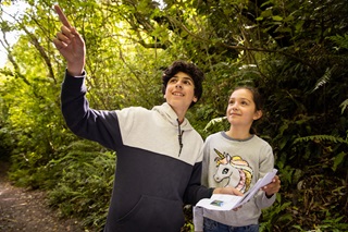 Two children, holding a map, pointing and looking for wildlife at Zealandia.