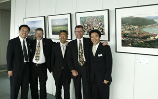 Five men in suits standing in front of four framed images of Wellington. The images were selected by photographer Neil Price, who is pictured second from right, as part of an exhibition showcasing Wellington in the Japanese city of Sakai.