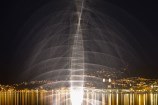 A photo of the Len Lye water sculpture, tall and brightly lit, on Wellington waterfront at night time.
