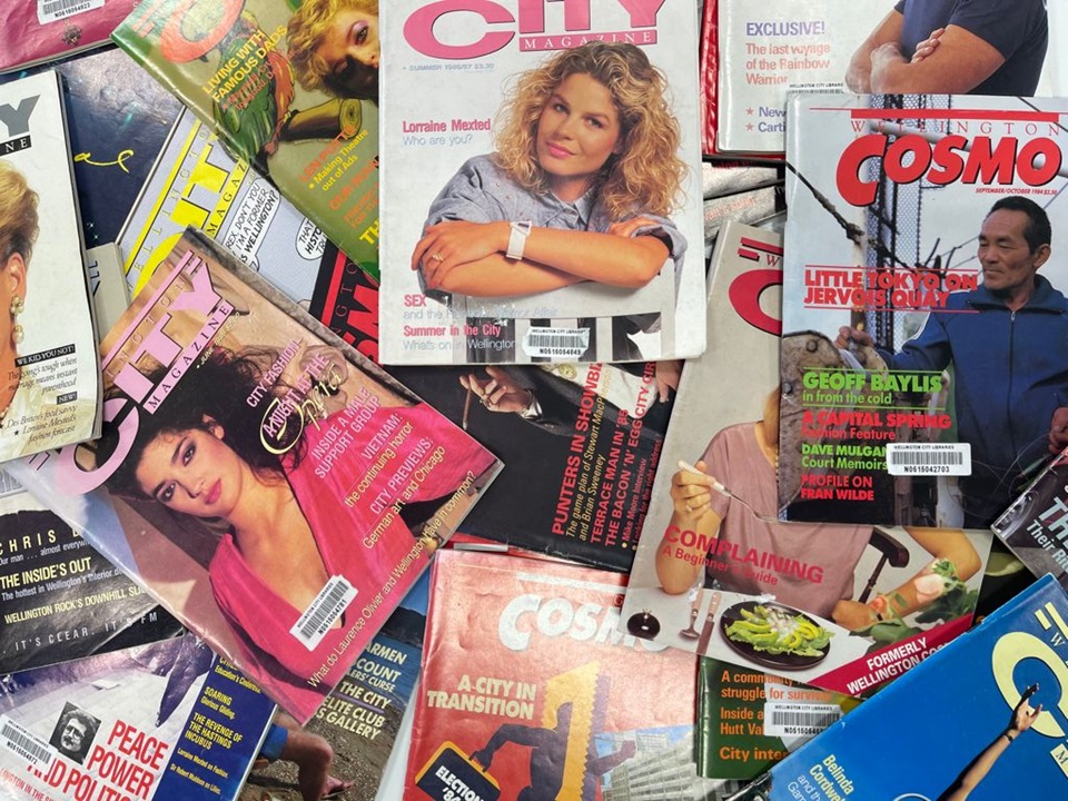 Photograph of a pile of colourful magazines from the 1980s spread across a table.
