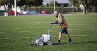 Dave Jackson uses a line marker to paint white lines on the field at Miramar's Polo Ground.