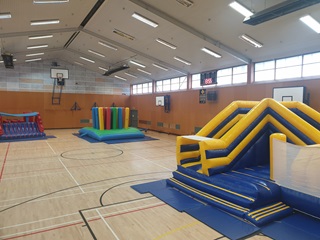 Three large inflatable playgrounds inside a recreation centre.