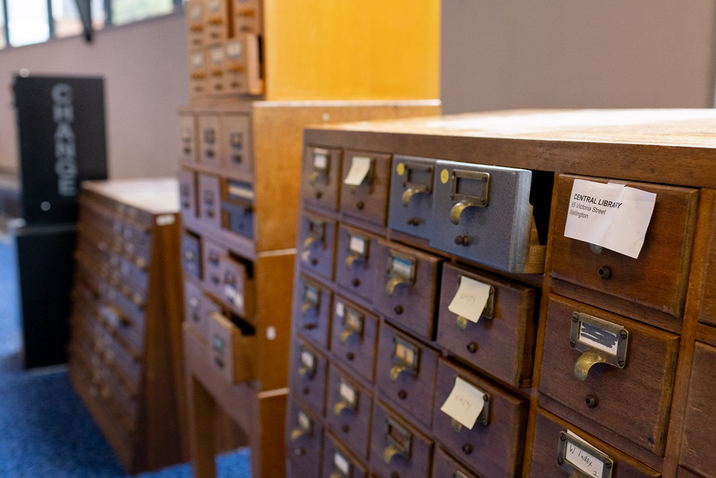 Three large standing wooden rolodexes with small drawers each labeled with a written note.