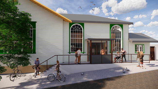 The Newtown community hub building, with large chapel-like dome windows, and people, some with bikes, hanging out outside in the sun.