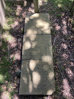 A gravestone in three slabs on the ground.