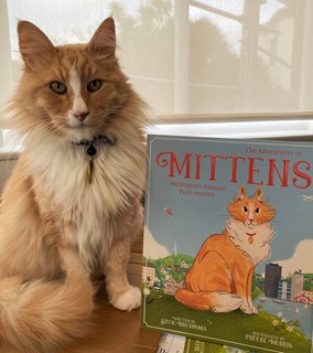 Mittens the cat sitting next to the book inspired by his life.
