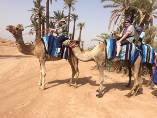 Raewyn and her partner Peter riding on camels in the desert in Morocco.